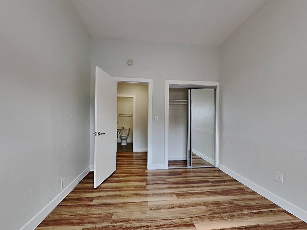 a bedroom with a door to a closet and a hard wood floor