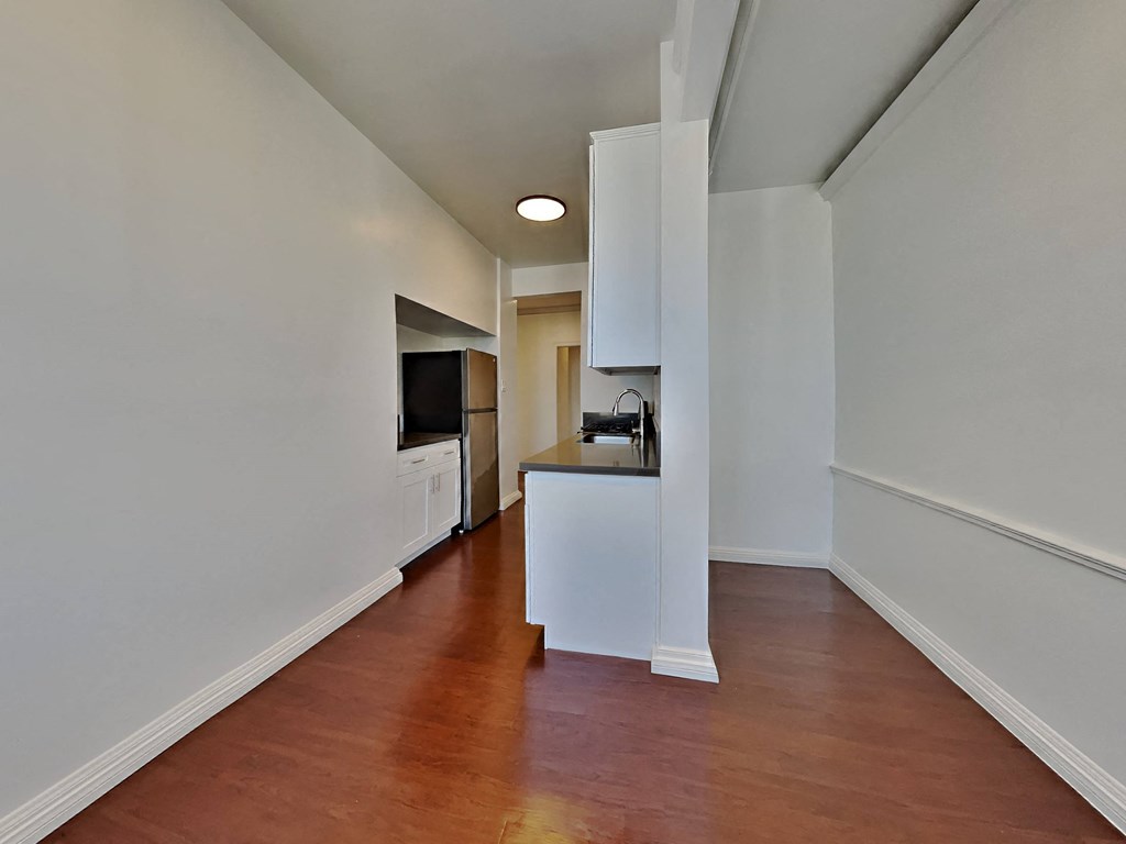 a living room and kitchen with wood floors and white walls