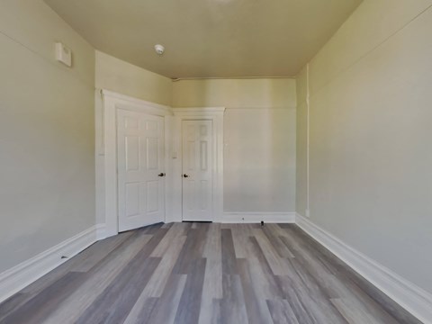 a living room with white walls and wooden floors and two doors