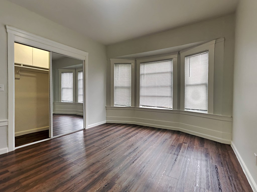 an empty living room with wood floors and windows