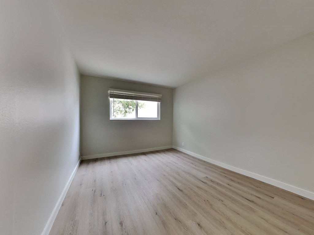 an empty room with wooden floors and a window