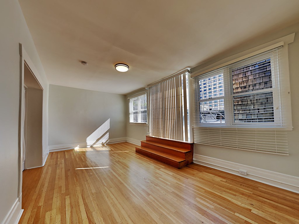 an empty living room with a staircase and a large window