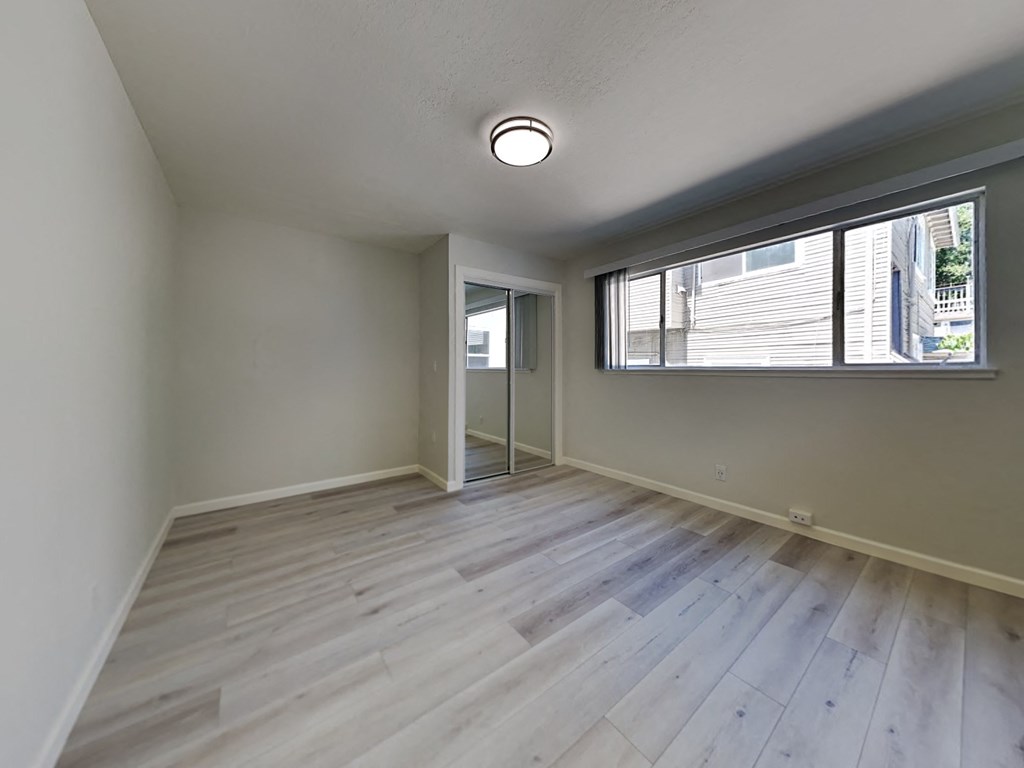 an empty living room with wood flooring and a large window