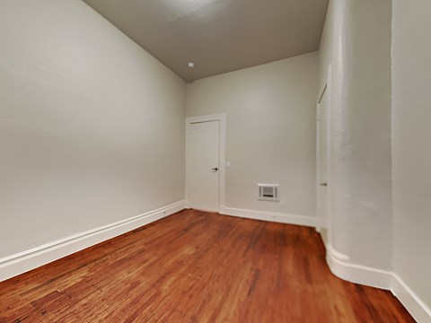 a bedroom with wood flooring and white walls