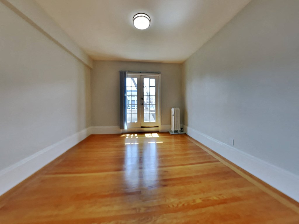 an empty living room with a wood floor and a door