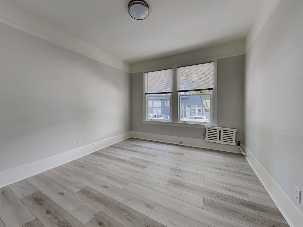 an empty room with wood floors and a window