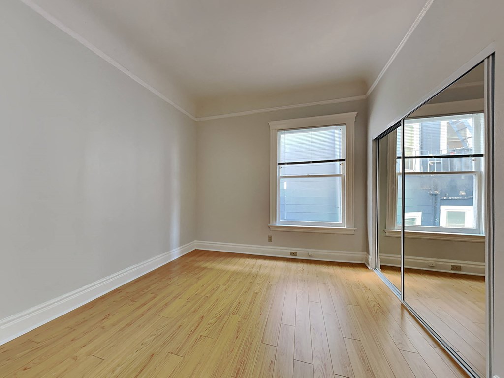 an empty living room with a mirror in the corner