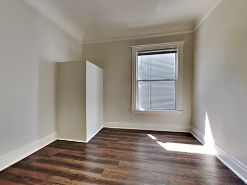 an empty room with wooden floors and a window