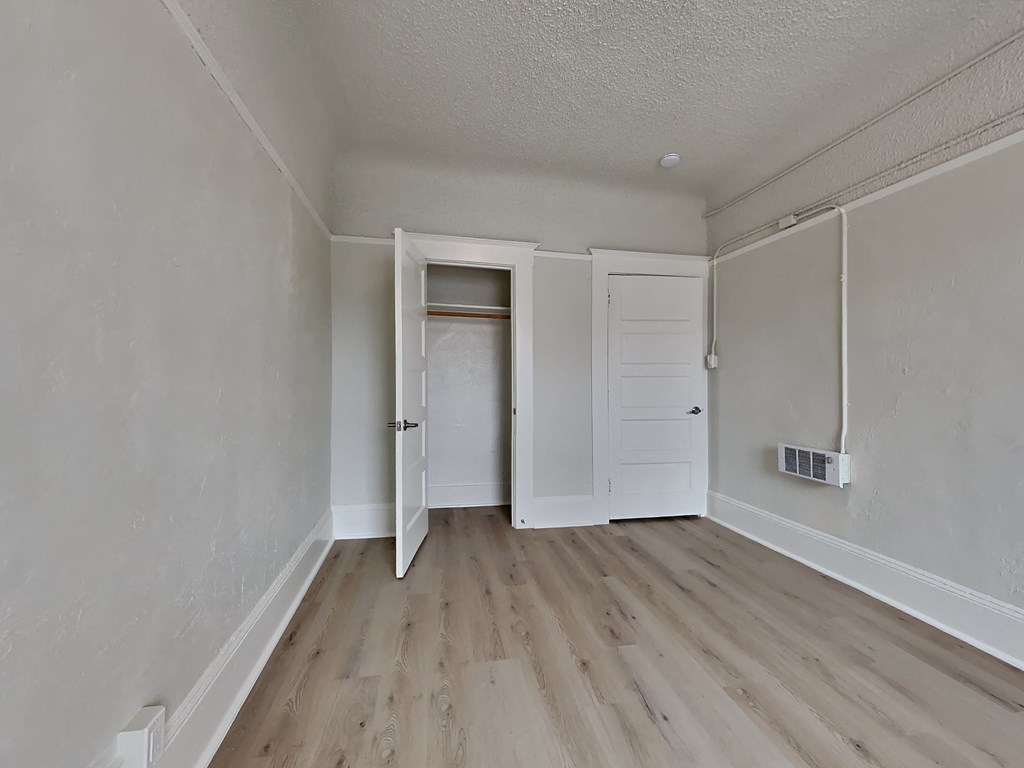 the living room of an empty apartment with wood floors and white walls