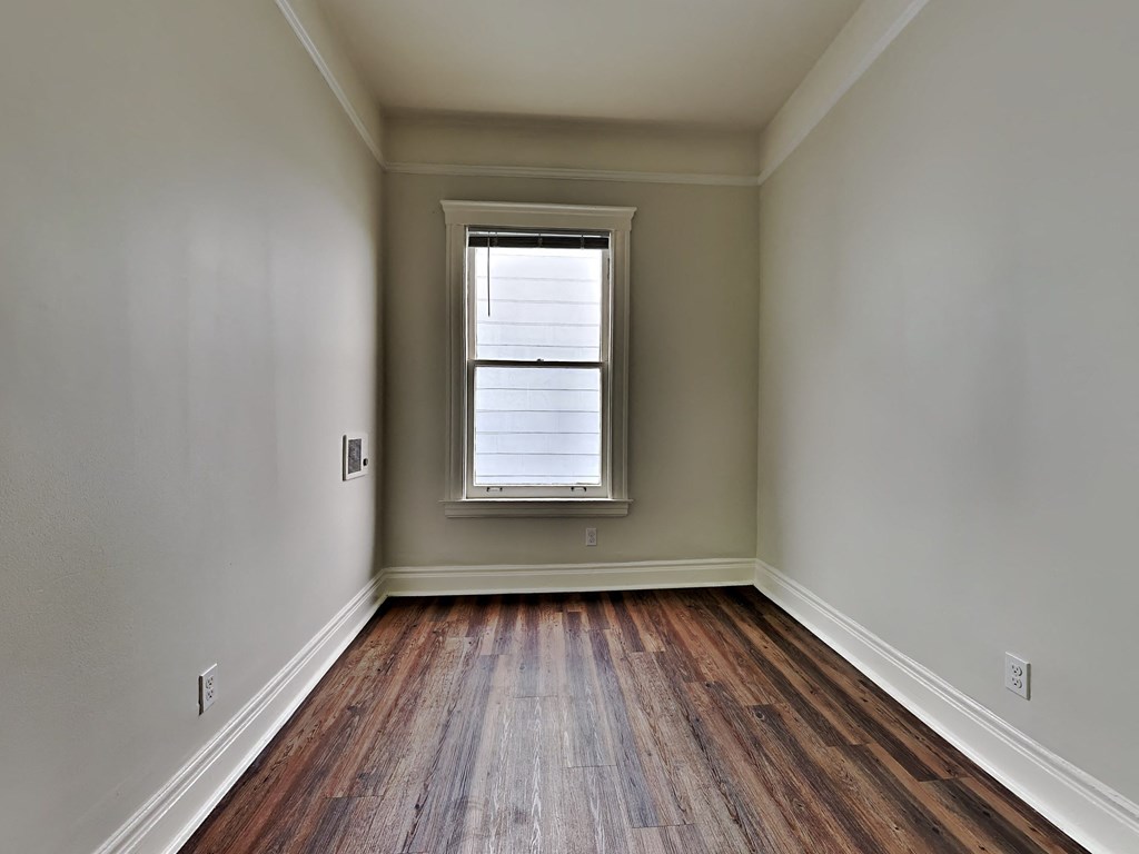 an empty room with wood floors and a window