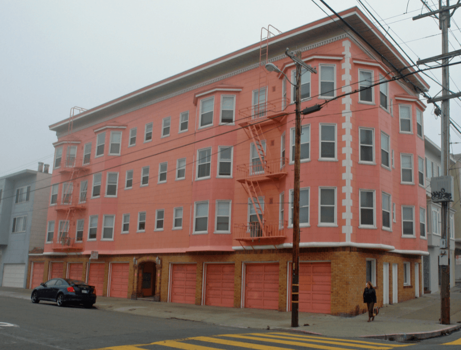 a large pink building on a city street