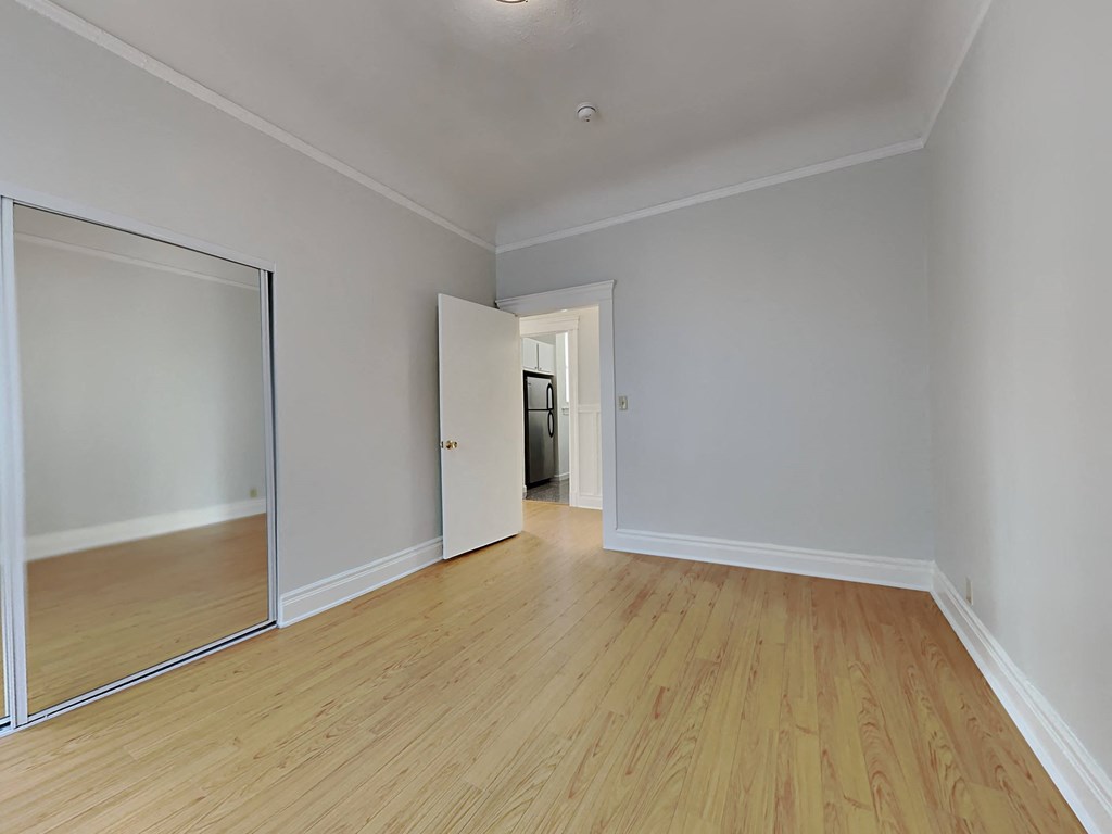 a living room with wood floors and a door to a hallway