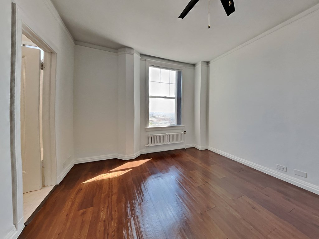 an empty living room with wood floors and a window