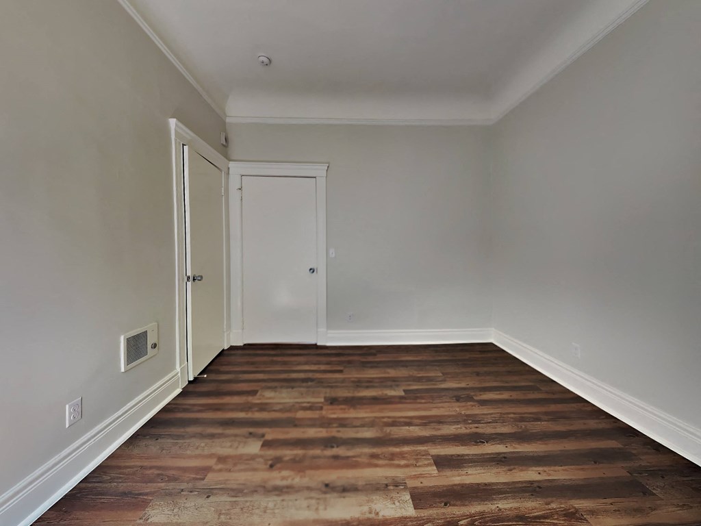 a room with wood flooring and white walls and a door