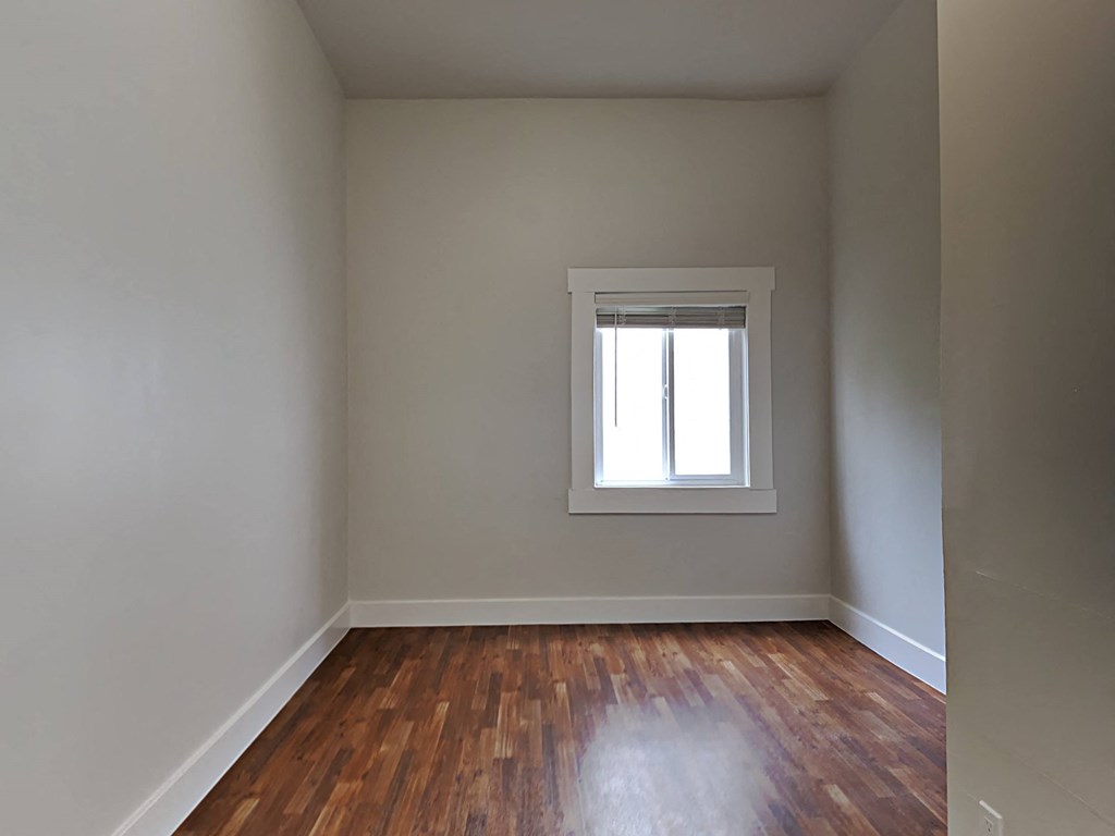 a empty room with a window and wooden floors