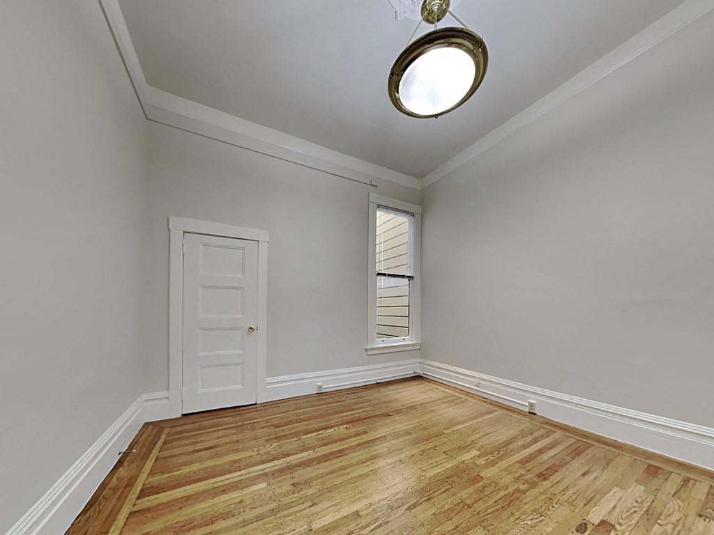 an empty living room with a white door and a window