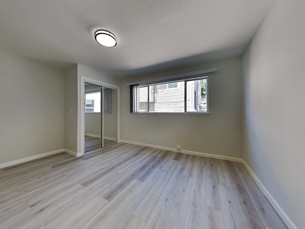 an empty living room with wood floors and a window