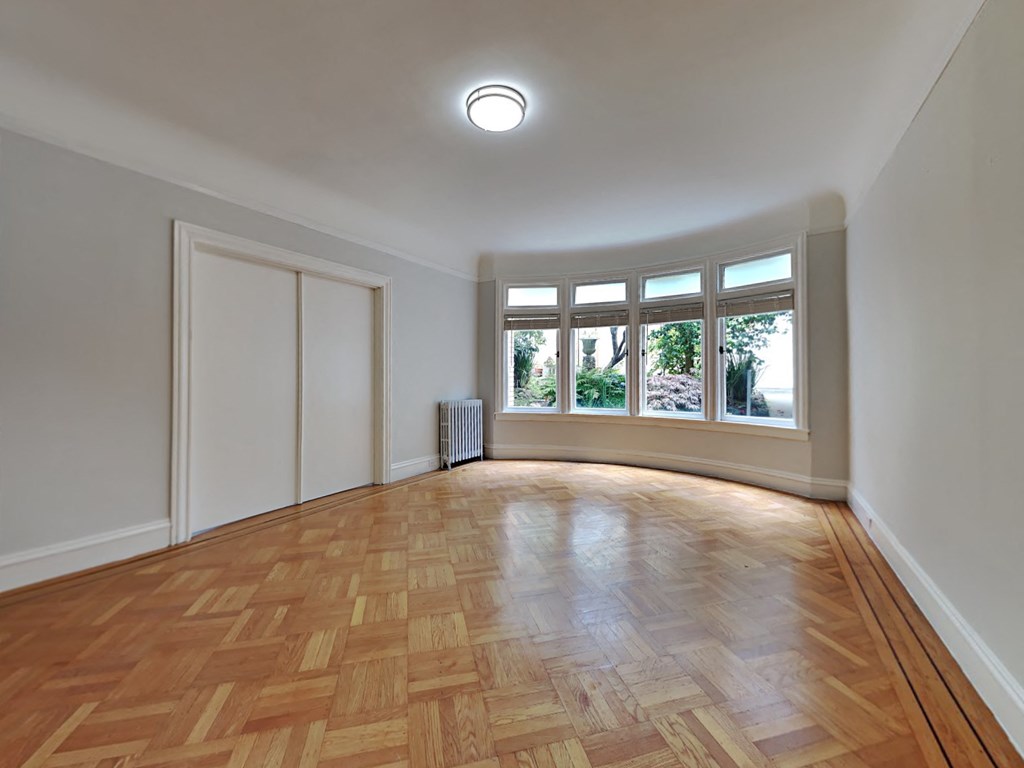 an empty living room with a large window and wooden floors