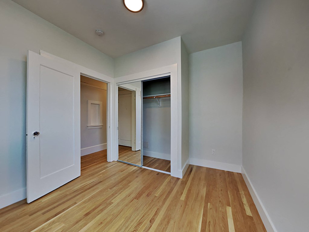 a bedroom with a closet and a mirrored closet door