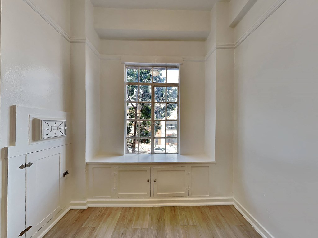 a living room with a large window and a white cabinet