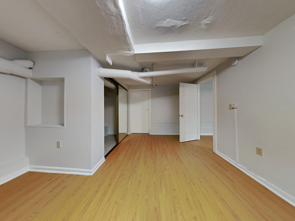 a living room with wood floors and white walls and a mirrored door