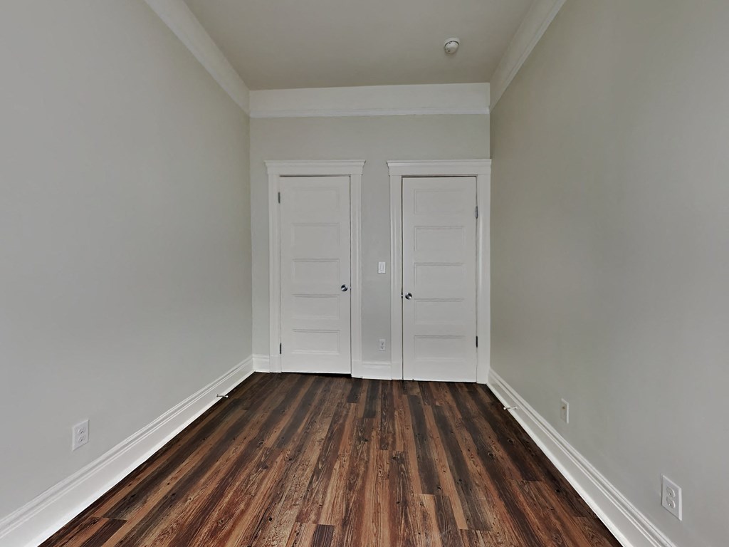 an empty room with wooden floors and two doors
