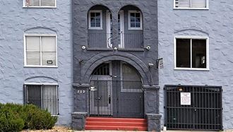 a blue building with a black door and a gate