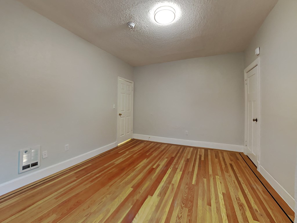an empty living room with wood flooring and white walls