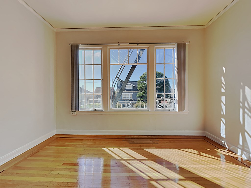 an empty living room with a large window and wooden floors