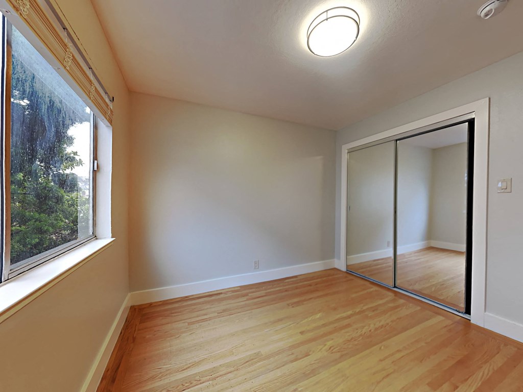 an empty living room with a large window and a mirrored closet