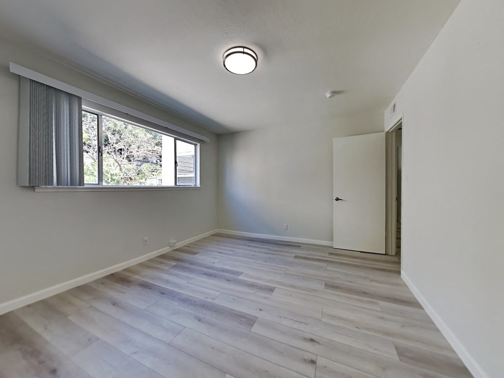 an empty living room with a large window and white walls