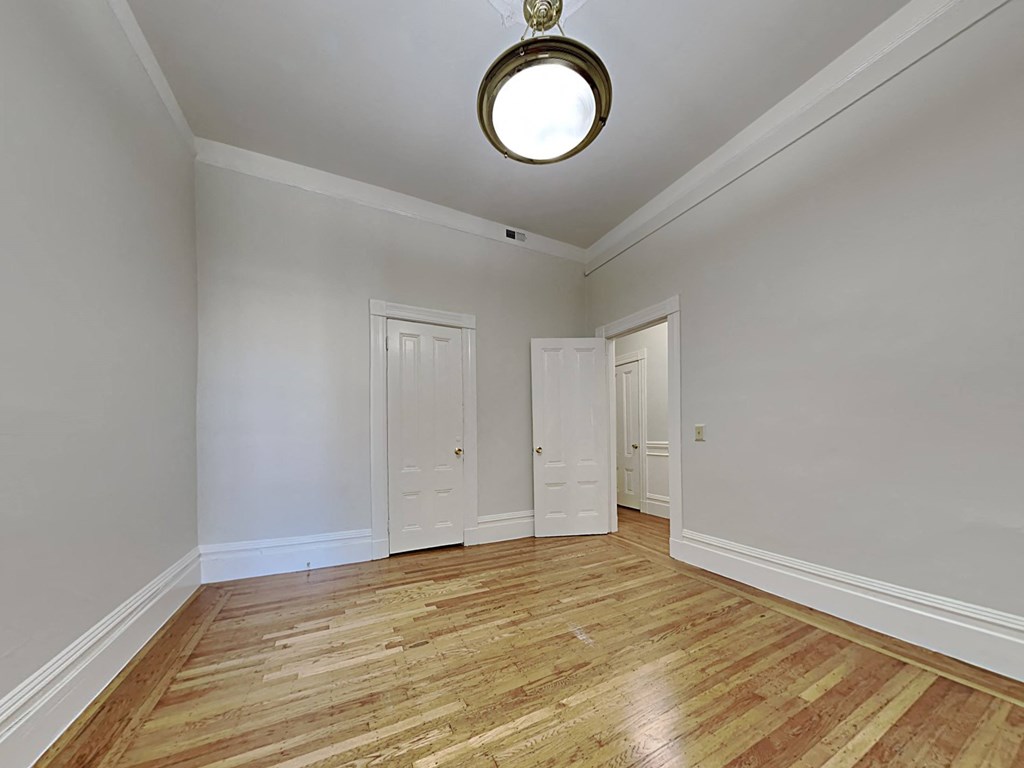 a living room with white walls and wood floors    and two doors