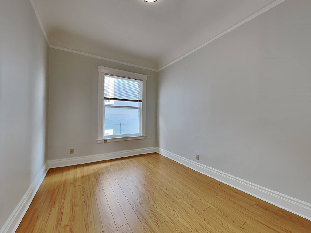 an empty room with wooden floors and a window