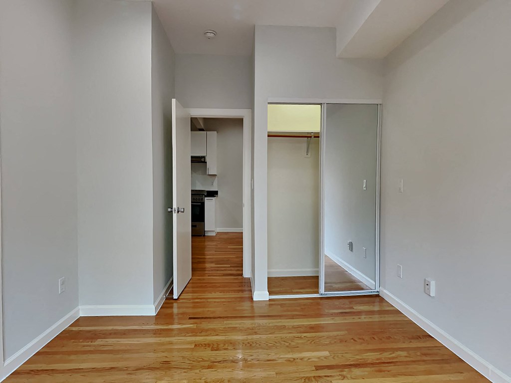 a renovated living room with wood floors and a hallway to a kitchen