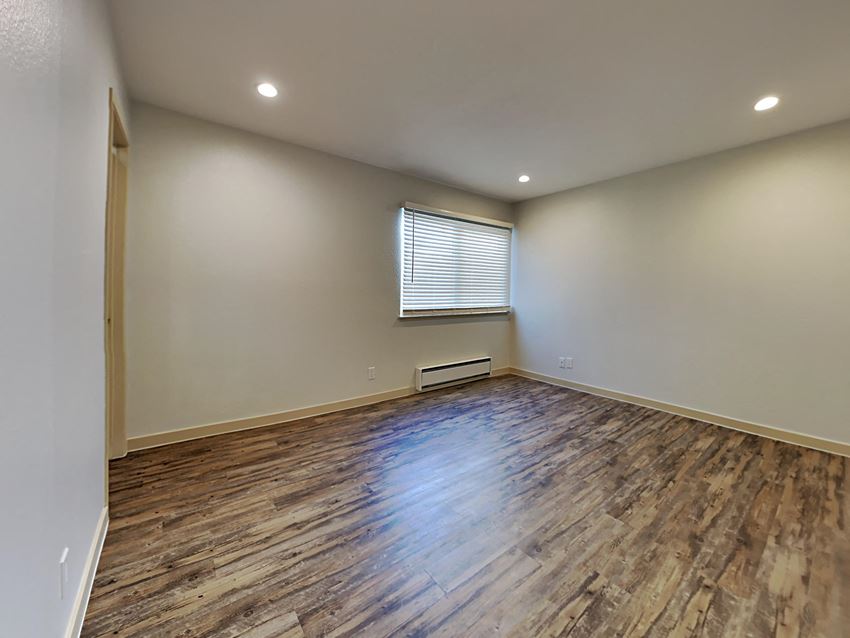 an empty living room with wood flooring and a window
