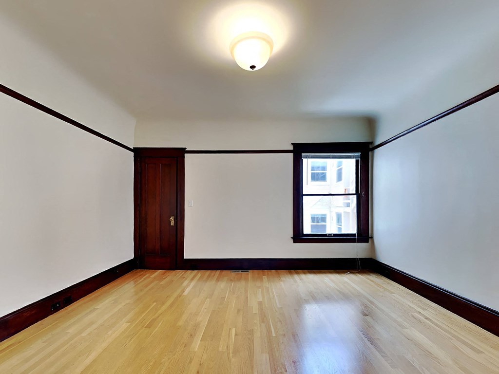 a living room with white walls and wood floors and a window