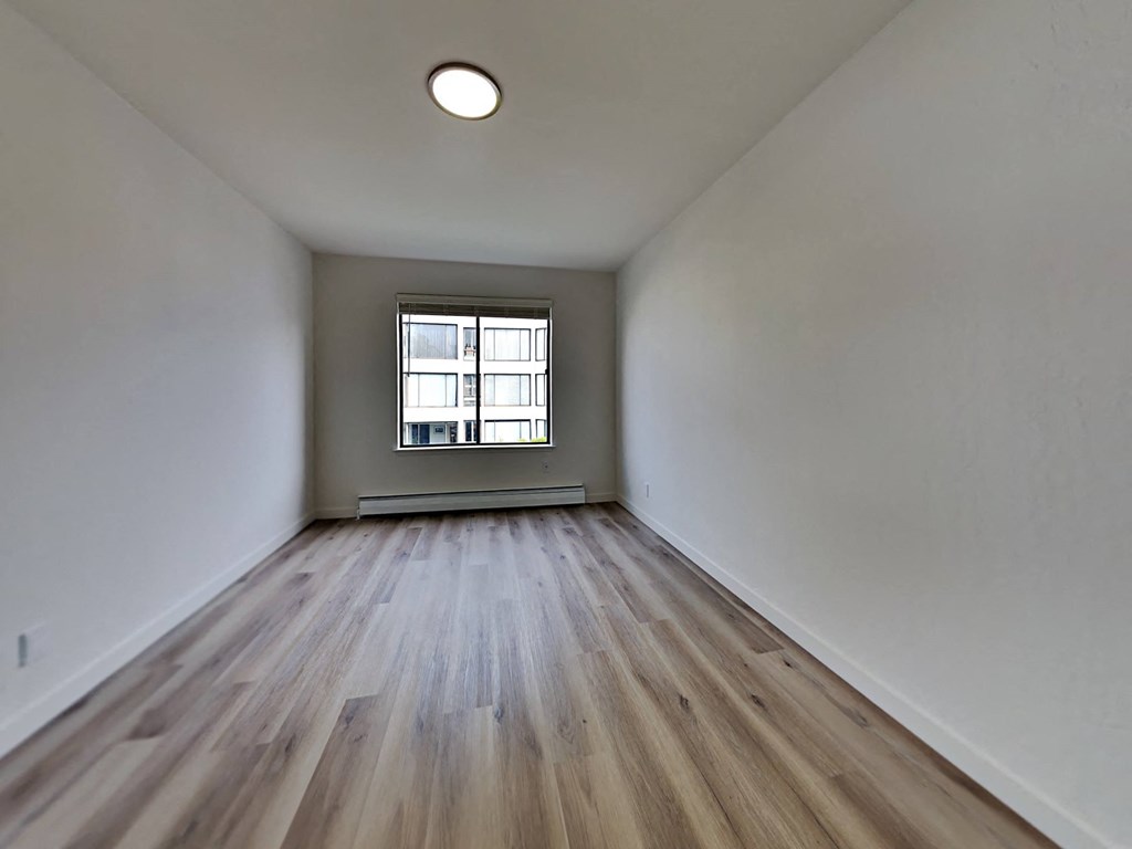 an empty room with wood floors and a window