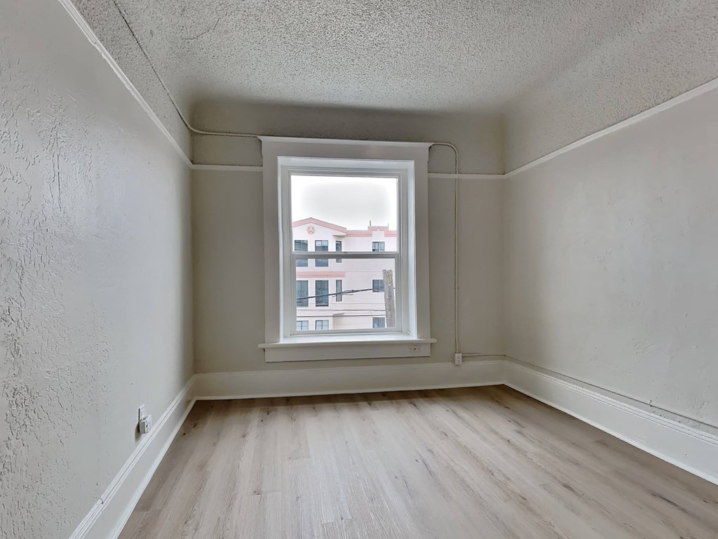 an empty room with a window and wooden floors