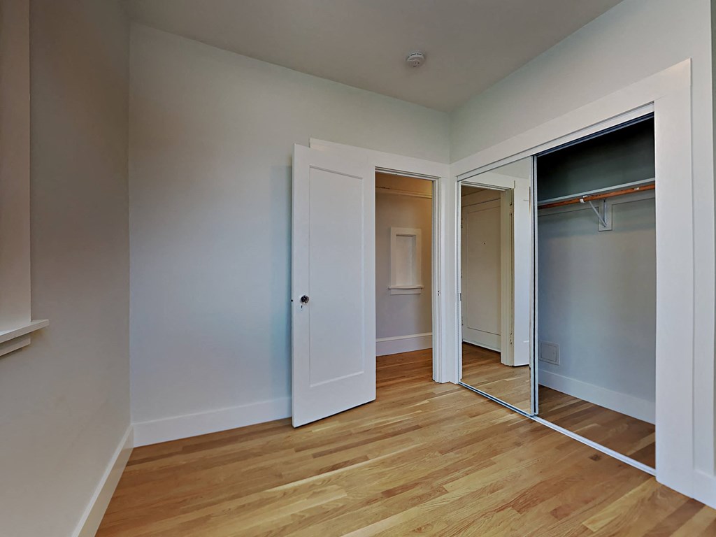 a bedroom with a mirrored closet and a hard wood floor