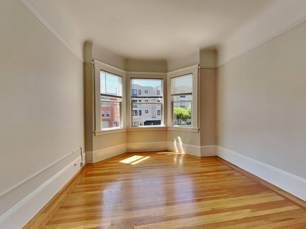 an empty living room with three windows and wood floors