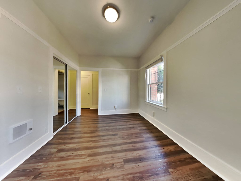 a empty living room with wood floors and a window