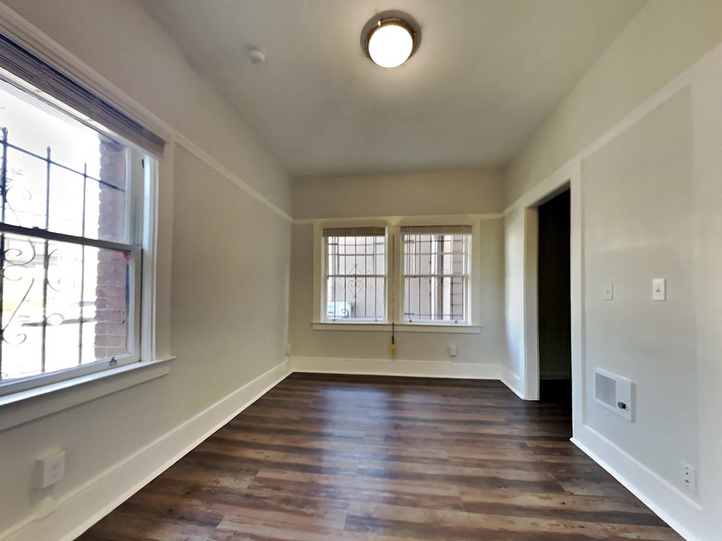 a empty living room with a large window and wooden floors