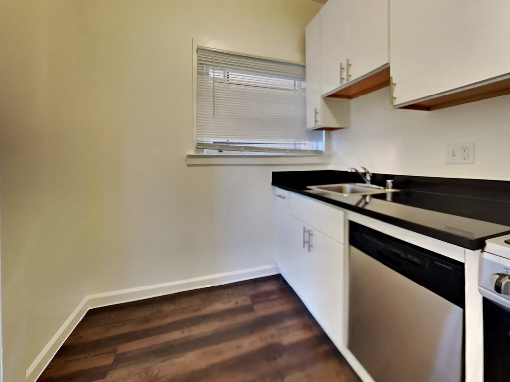 an empty kitchen with black countertops and white cabinets and a sink