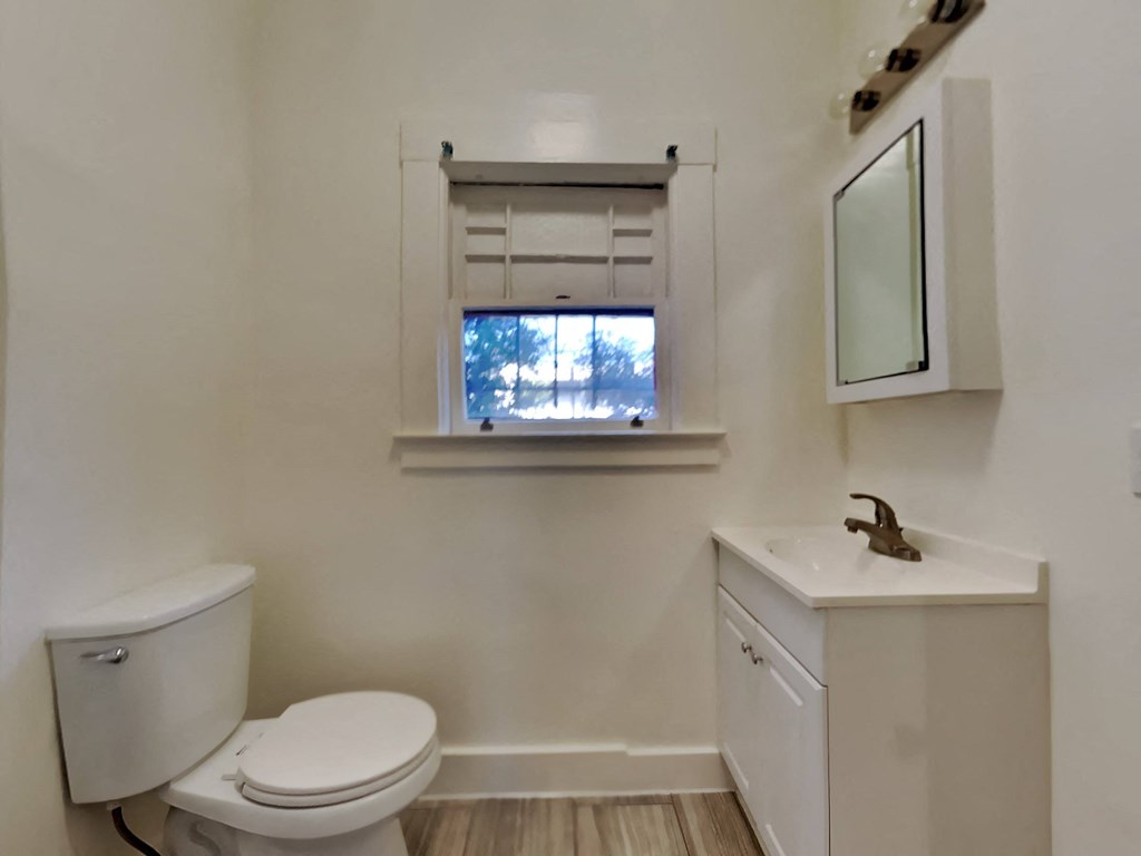 a bathroom with a toilet and a sink and a window