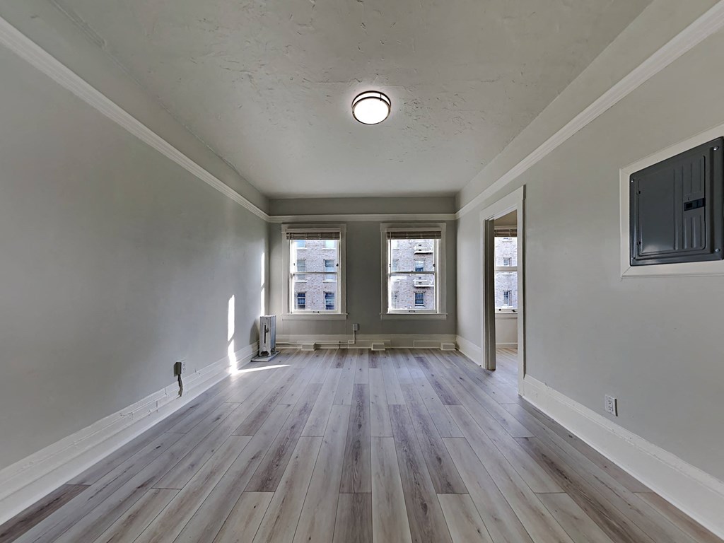 an empty living room with hardwood floors and two windows