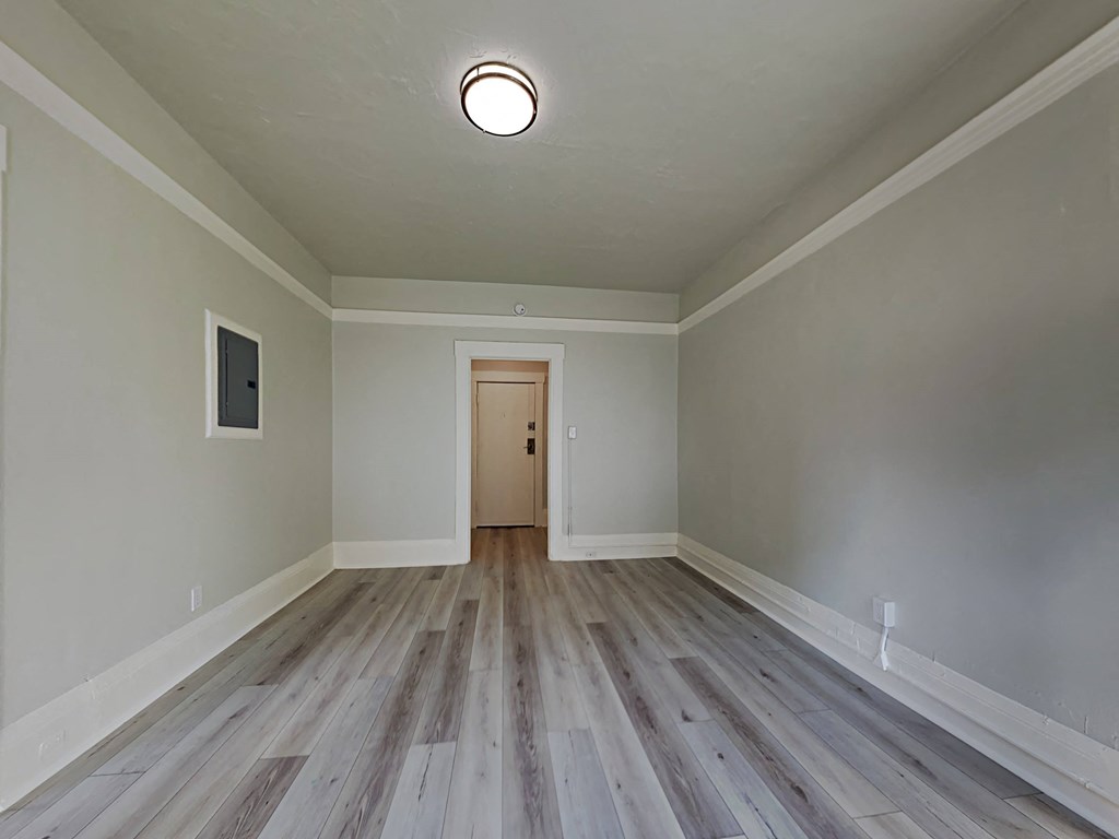 an empty living room with wood floors and a door to a hallway