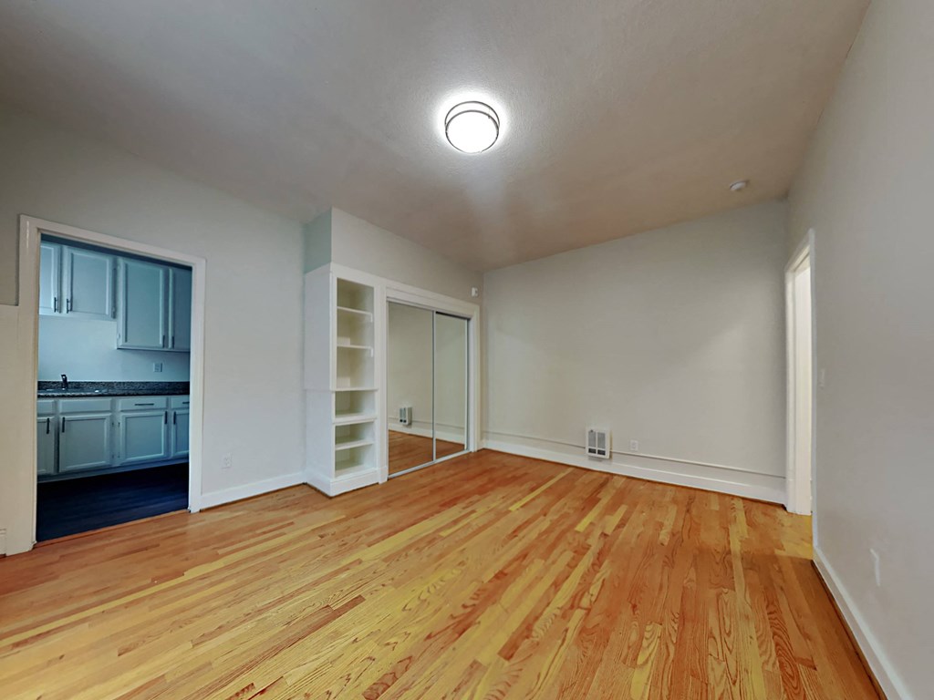 a living room with a wood floor and a door to a kitchen