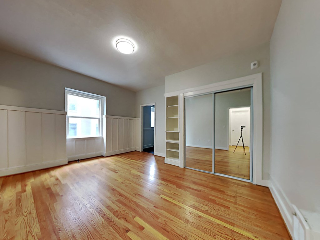 an empty living room with a large mirror and wood floors