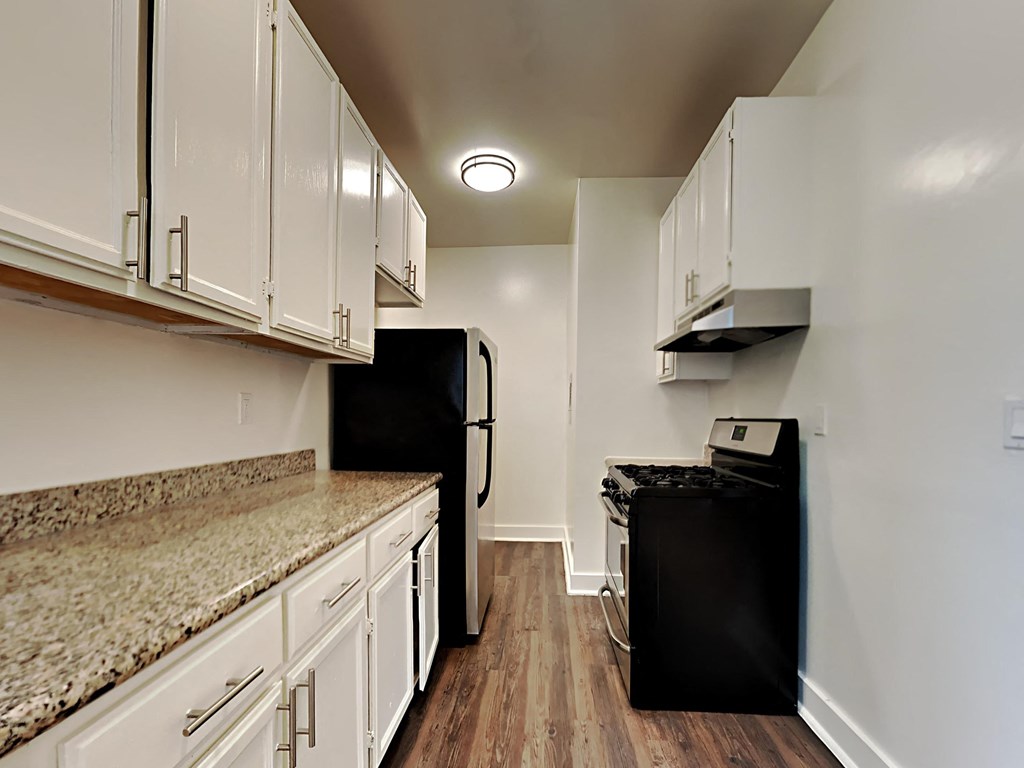 a kitchen with white cabinets and a black refrigerator