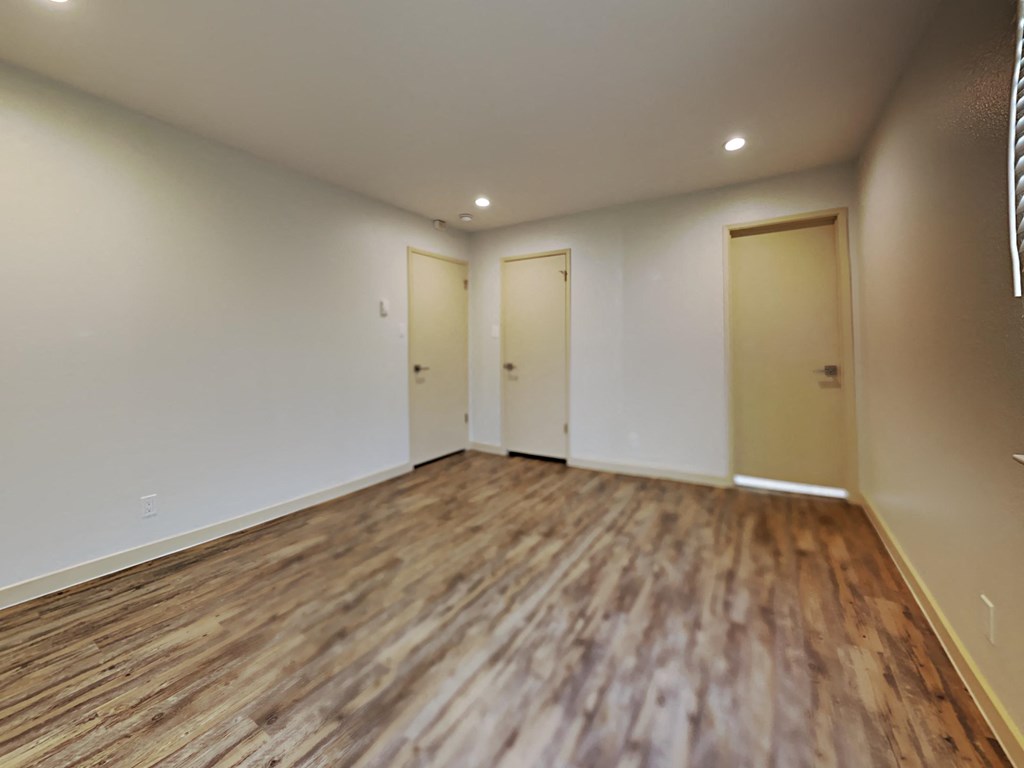 an empty living room with wood flooring and white walls